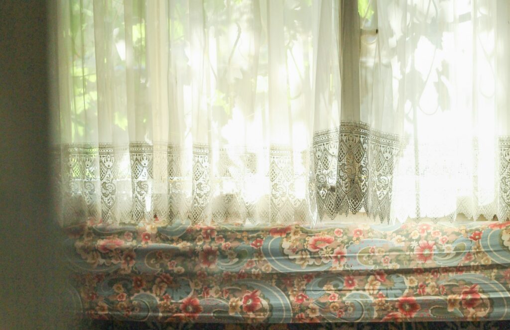 Fenêtre habillée de voilages avec banquette et lumière naturelle