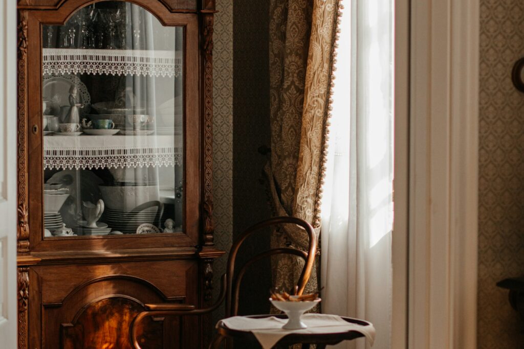 Meuble ancien en bois accompagné d'une chaise et d'une petite table dans une pièce de vie lumineuse